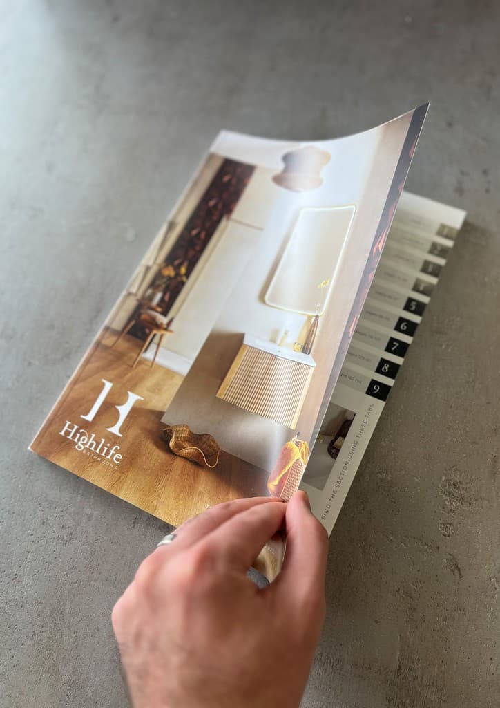 Geek Designs team member holding and reviewing the final, printed Highlife catalogue front cover