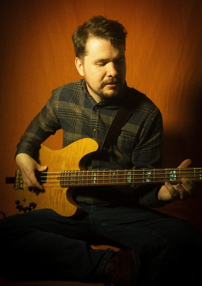 Chris the developer smiling and holding a bass guitar as a fun headshot.