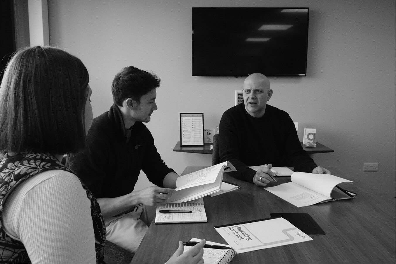 A meeting with the Marketing team reviewing a Marketing contract. From left to right: Ashleigh, Aaron, Ian.